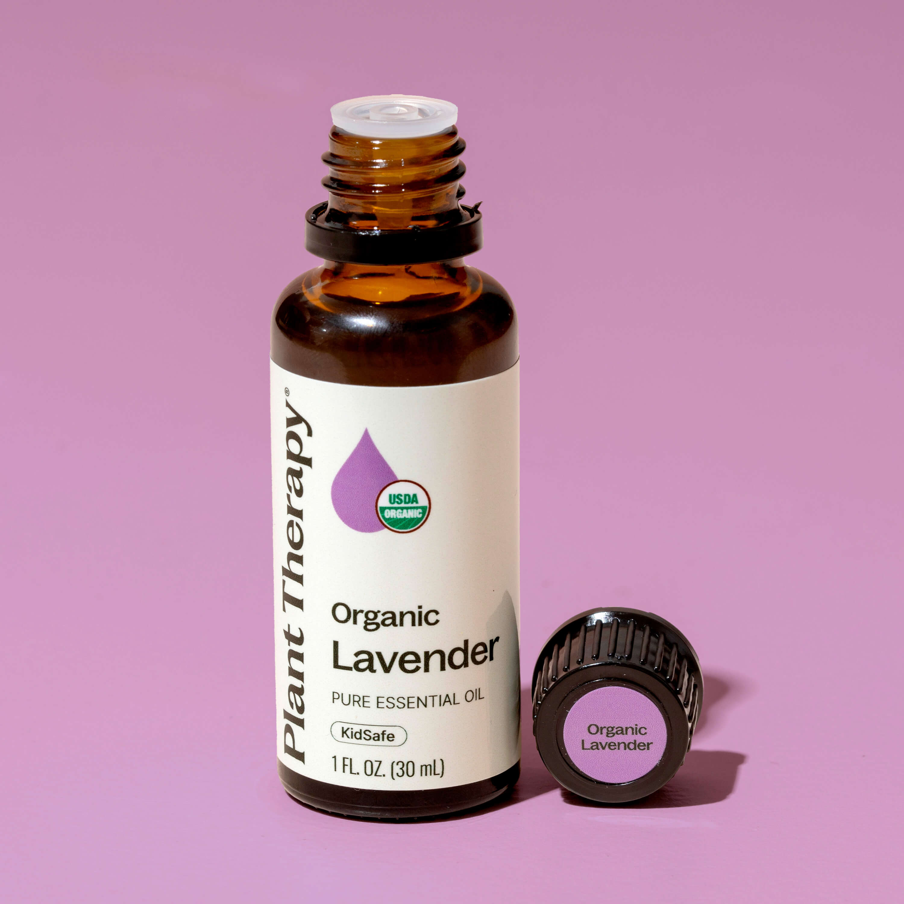 Bottle of Plant Therapy Organic Lavender essential oil on a pink background