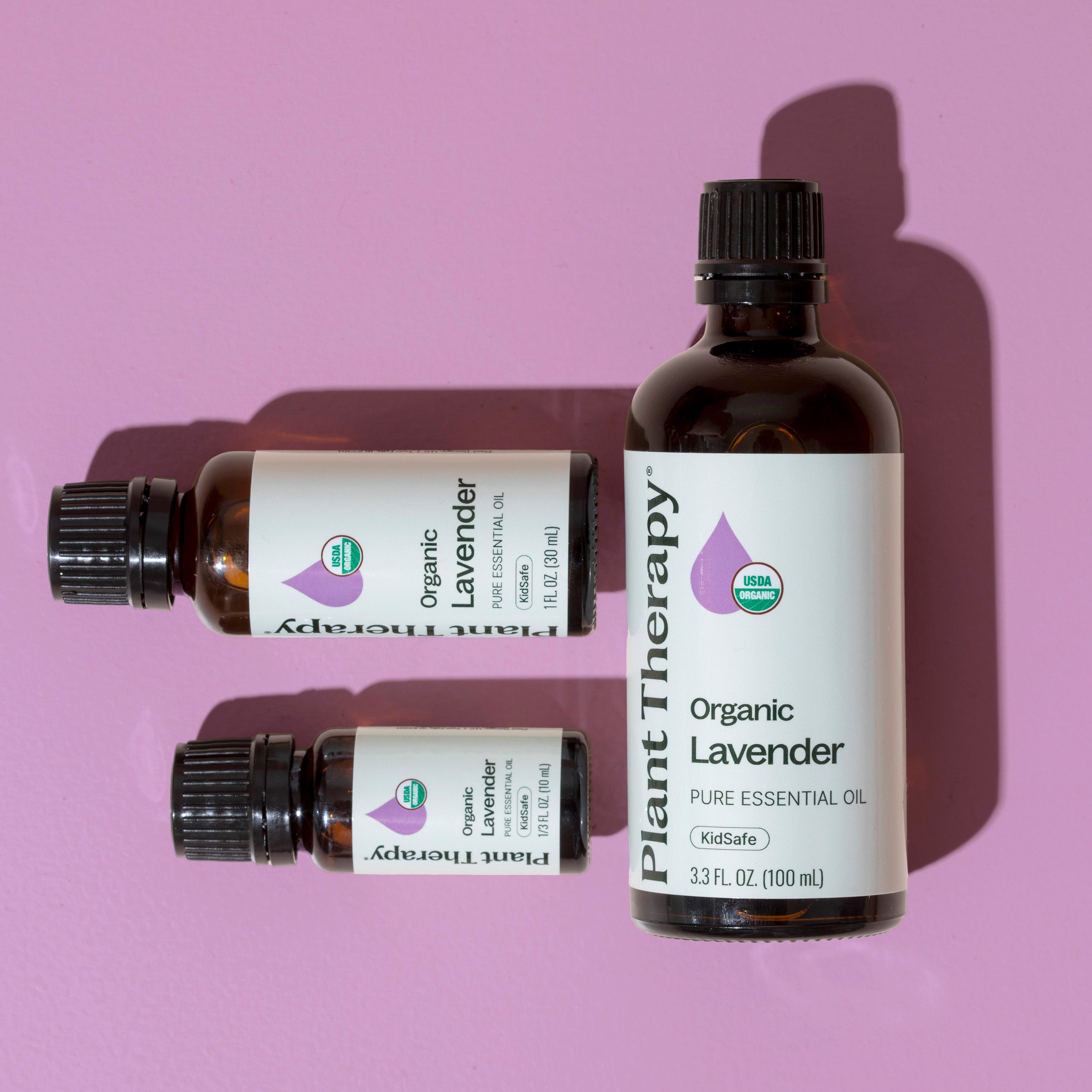 Three bottles of Plant Therapy Organic Lavender essential oil on a pink background