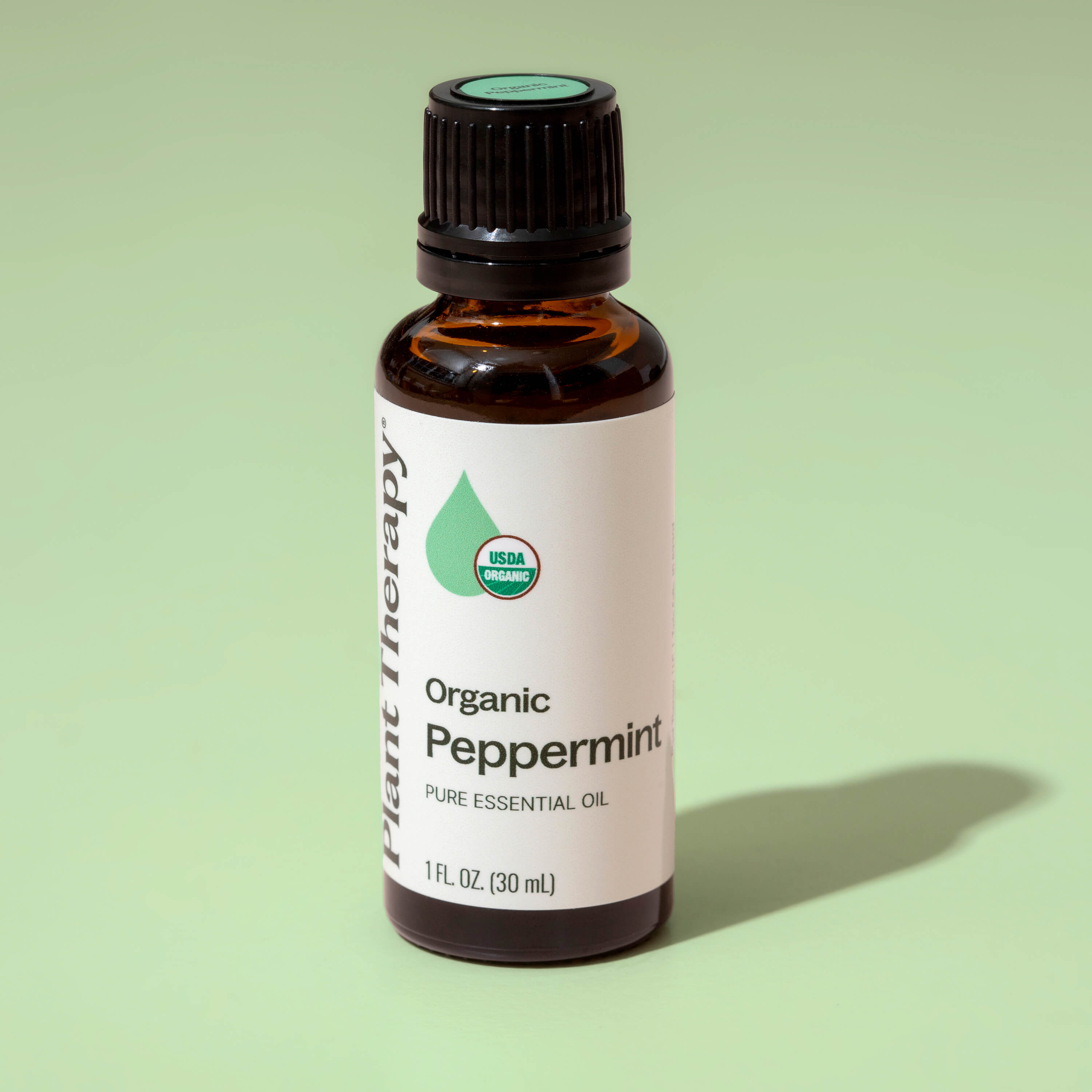 Bottle of Organic Peppermint Pure Essential Oil on a green background