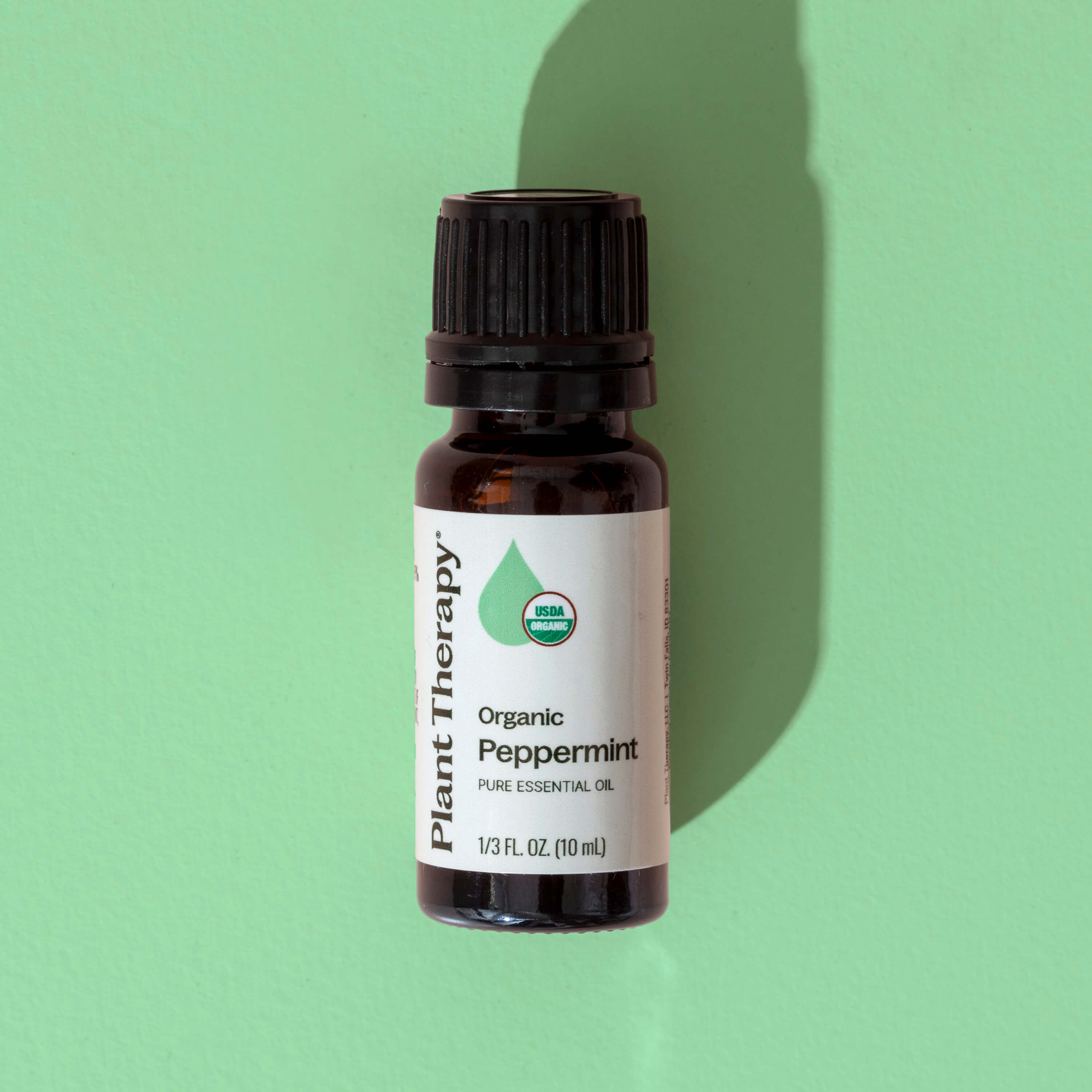 Bottle of Plant Therapy Organic Peppermint essential oil on a green background