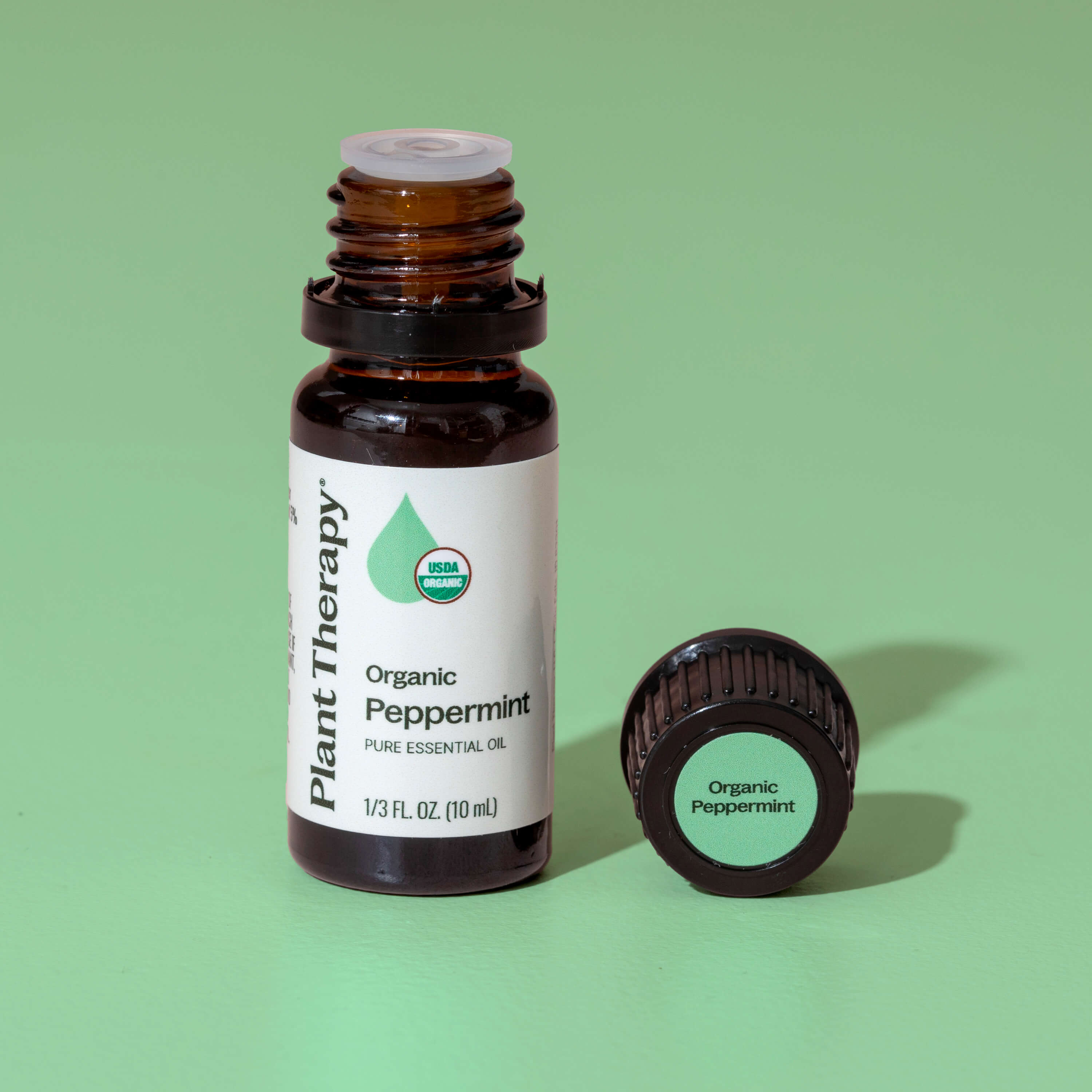 Essential oil bottle labeled 'Plant Therapy Organic Peppermint' on a green background