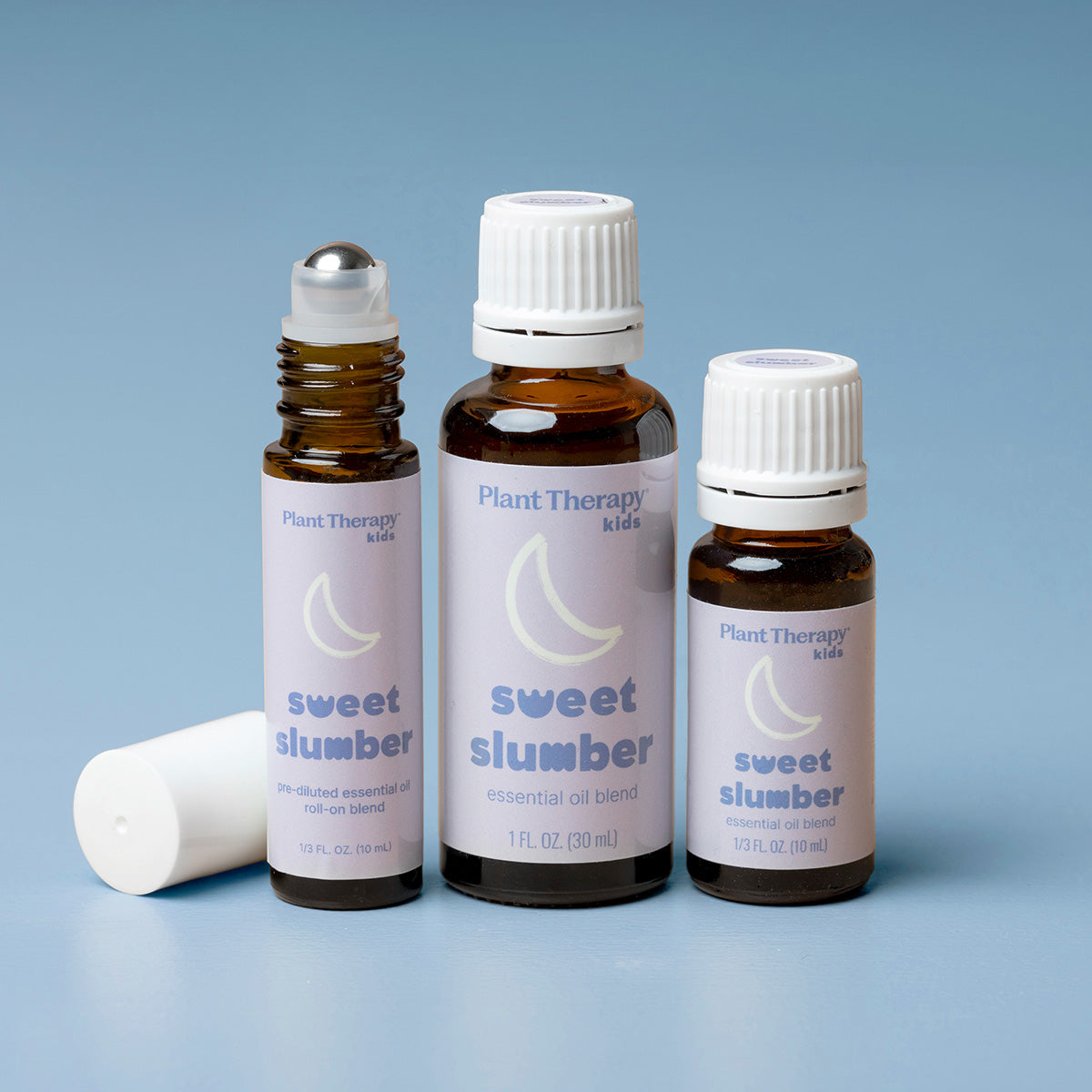 Three bottles of Plant Therapy 'sweet slumber' essential oil blend on a blue background
