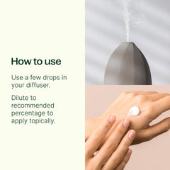 Hand applying a small amount of cream to wrist with diffuser in background