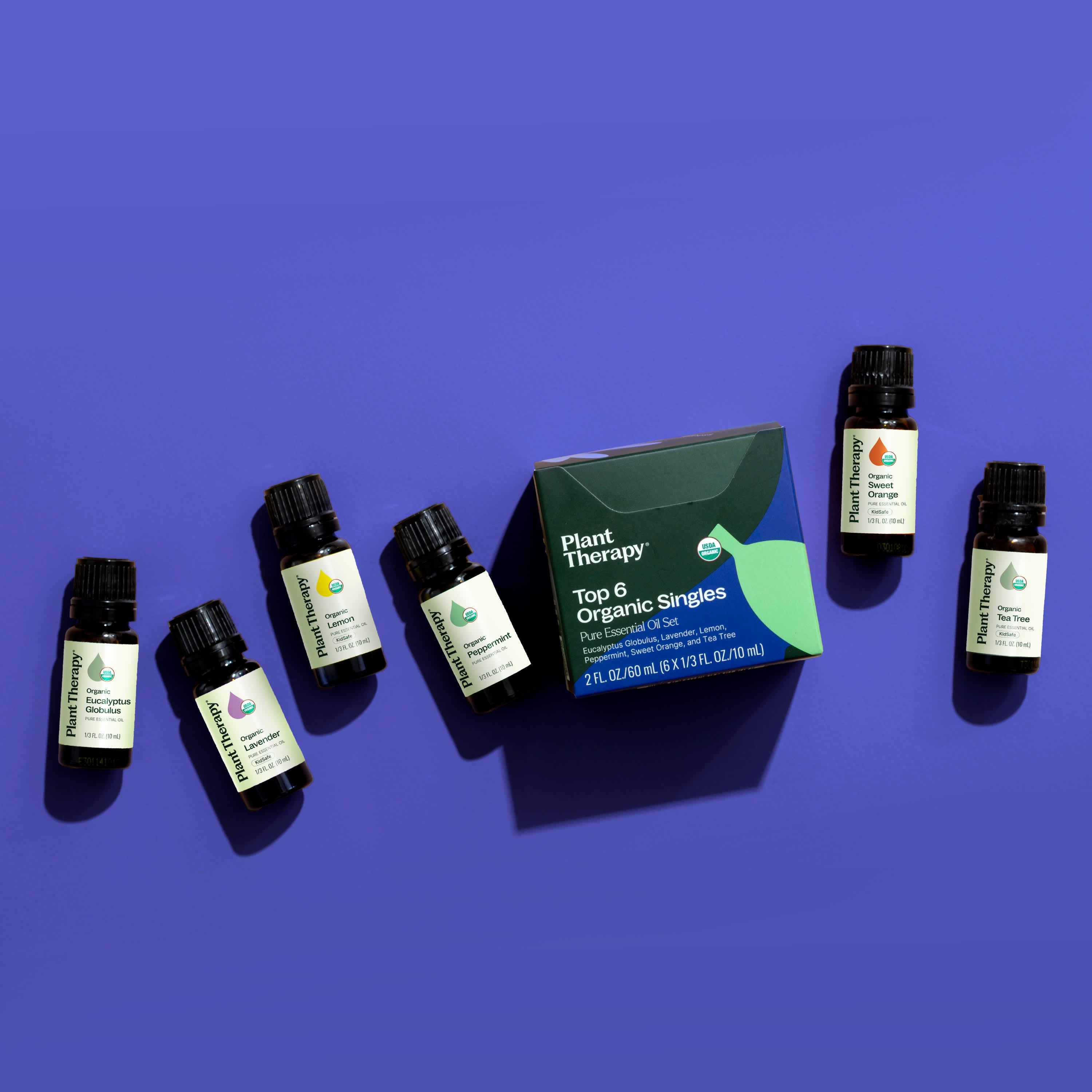 Collection of Plant Therapy essential oil bottles and packaging on a purple background