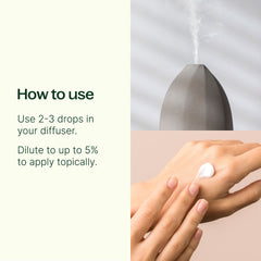 Hand applying a droplet of essential oil to wrist with diffuser in background