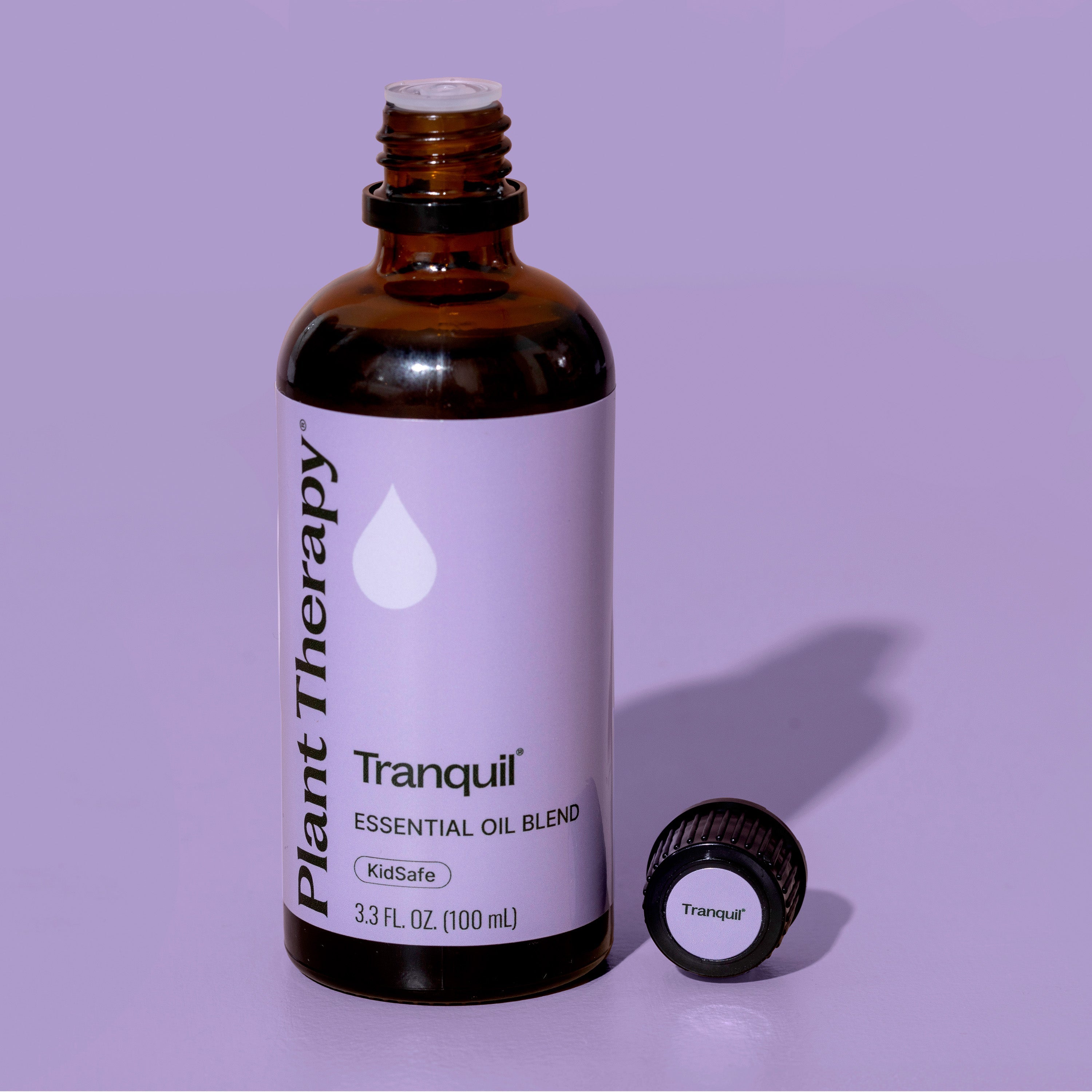 Brown bottle of Plant Therapy Tranquil essential oil blend on a purple background