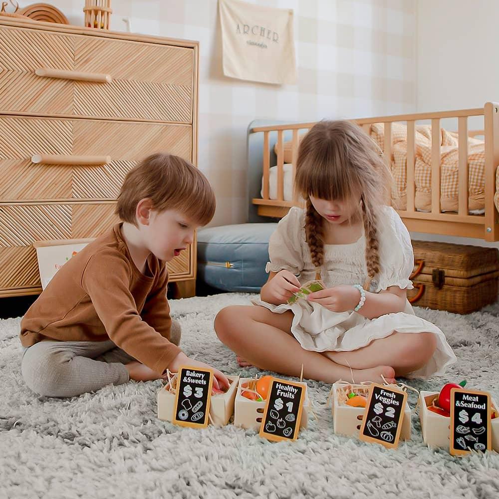 Two children playing with toy groceries in a bedroom setting.