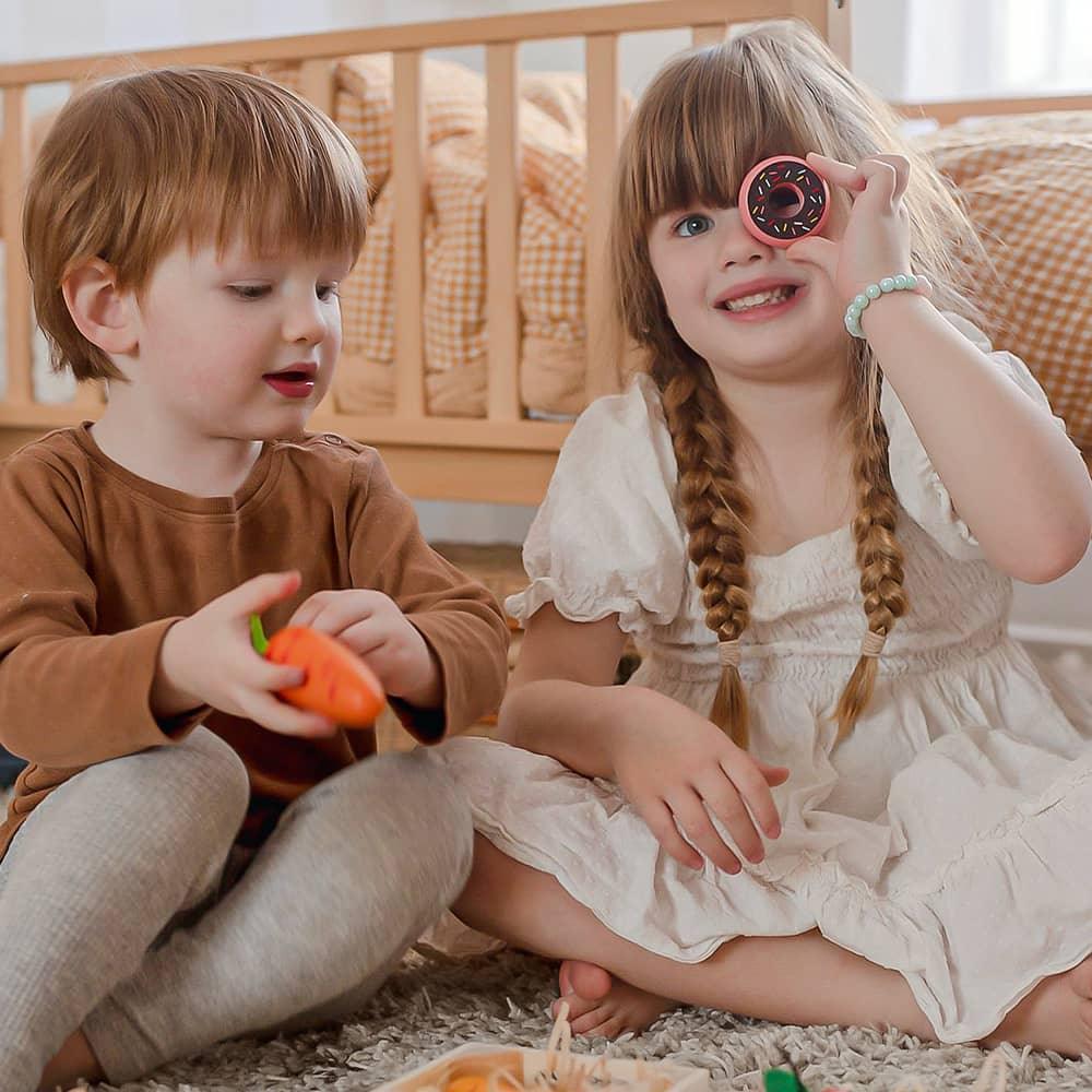 Two children playing with toys on the floor in a home setting.