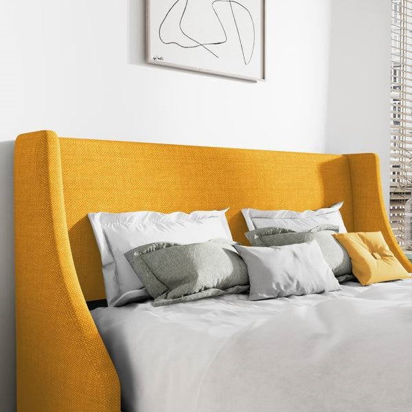 Yellow upholstered headboard with pillows in a bedroom setting