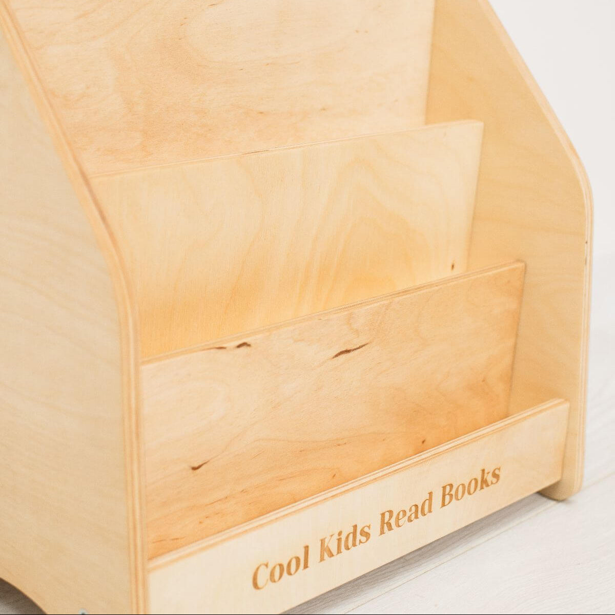 Wooden bookshelf with 'Cool Kids Read Books' engraving on a white background