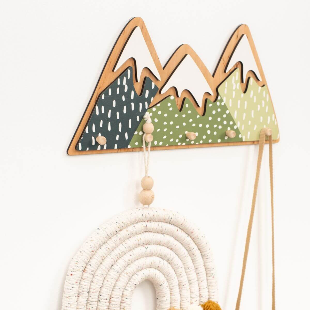 Decorative wall hanging with mountains and a rainbow on a white background