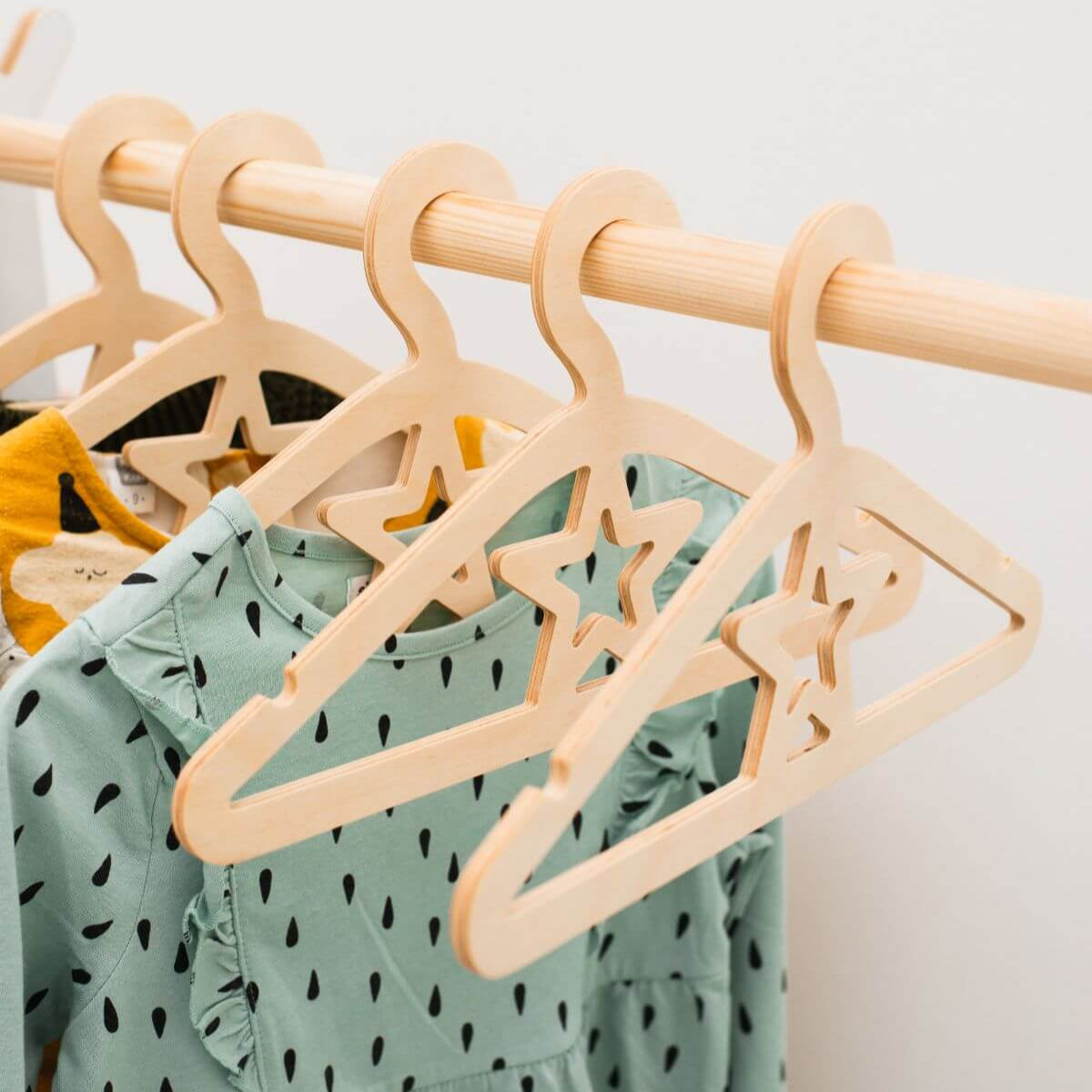 Wooden hangers with star designs on a rack with a green dress underneath.