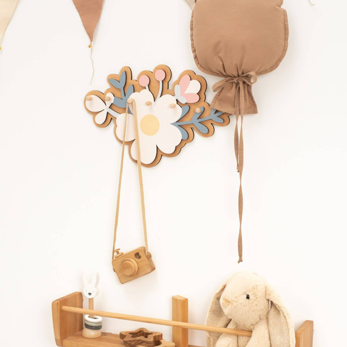 Decorative wall hook with floral design and camera attachment on a white wall.