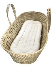 Woven baby Moses basket with white mattress on a white background