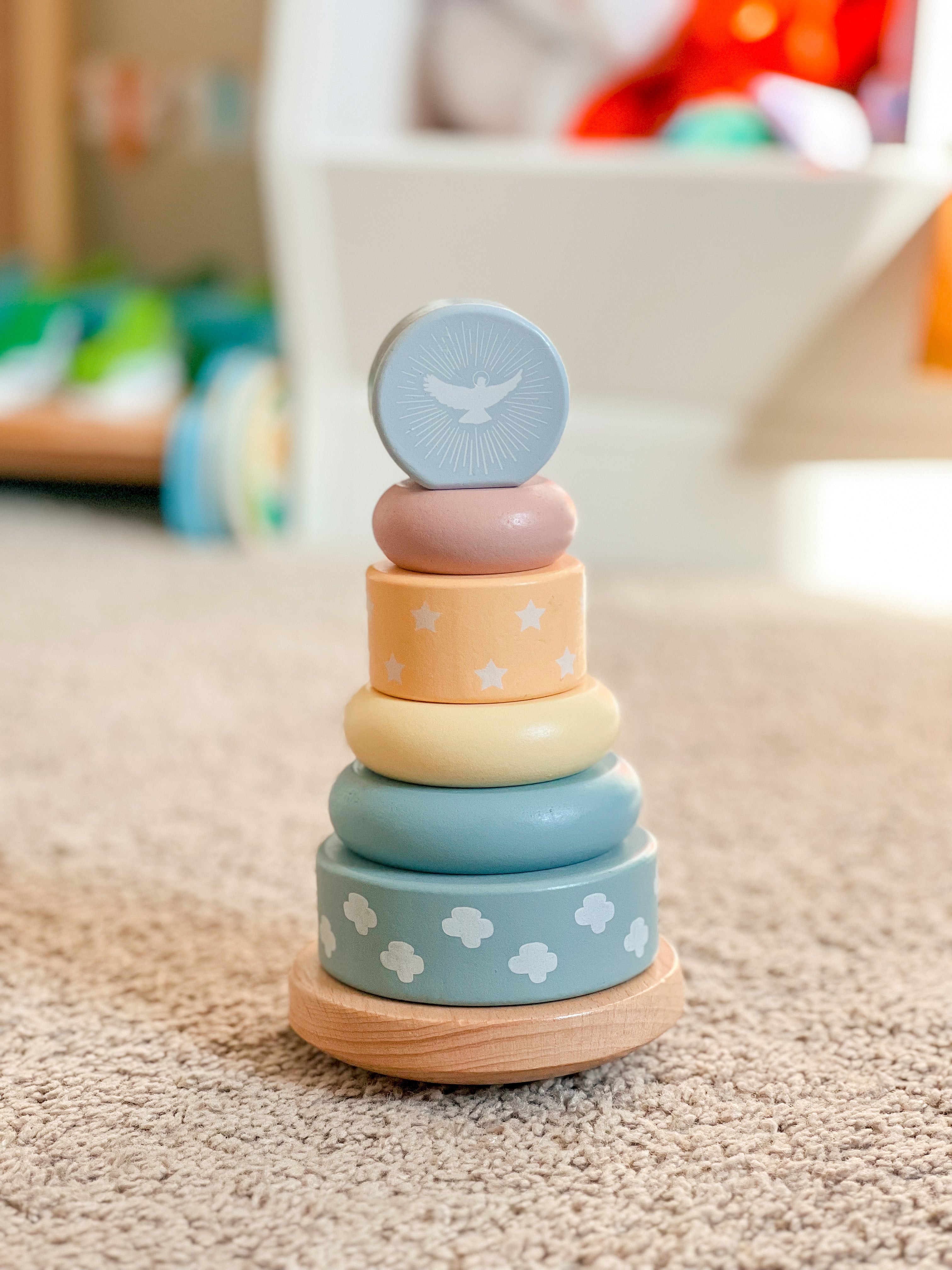 Stack of colorful wooden rings with a blue top on a carpeted floor.