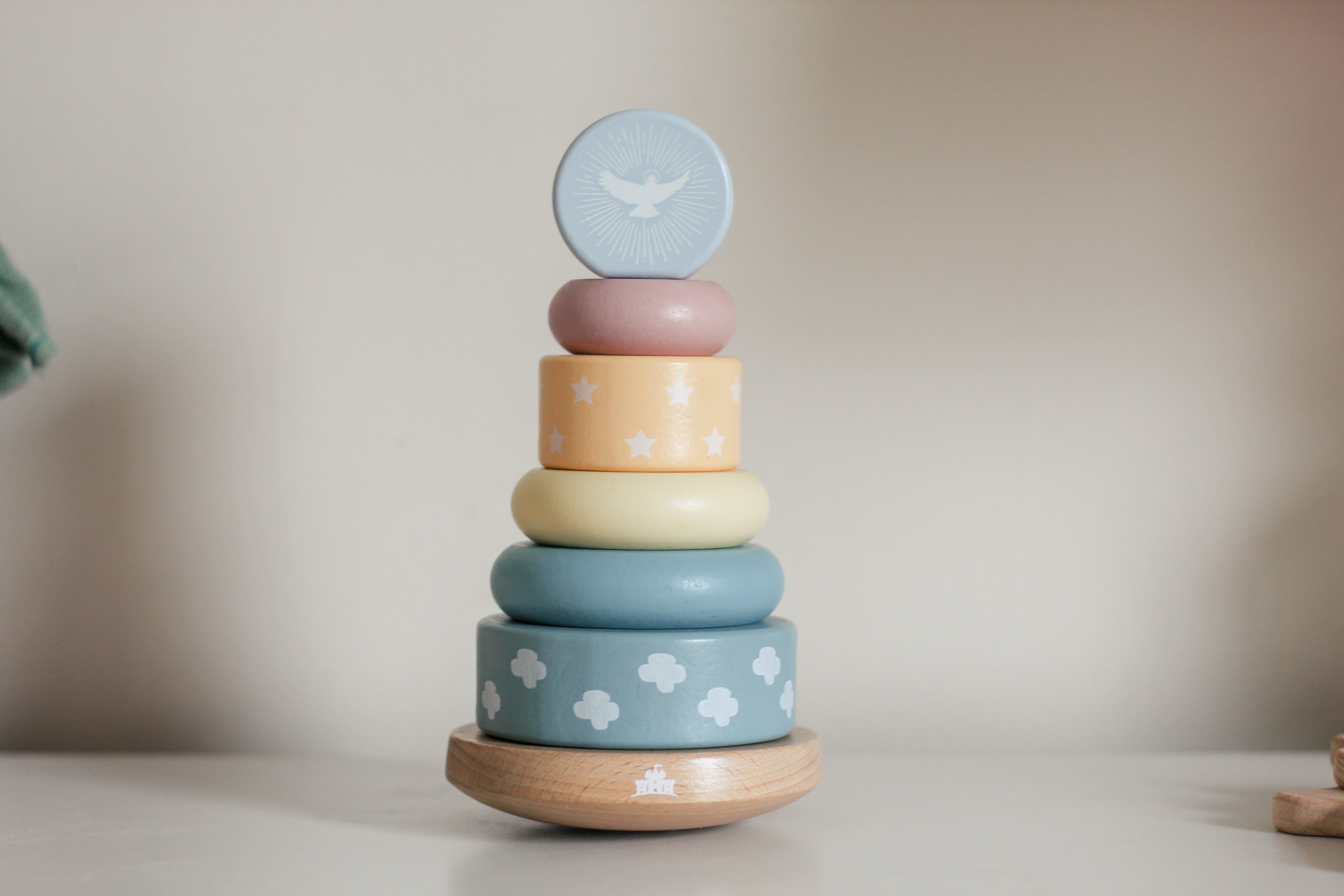 Stack of pastel-colored wooden rings with a bird design on a neutral background
