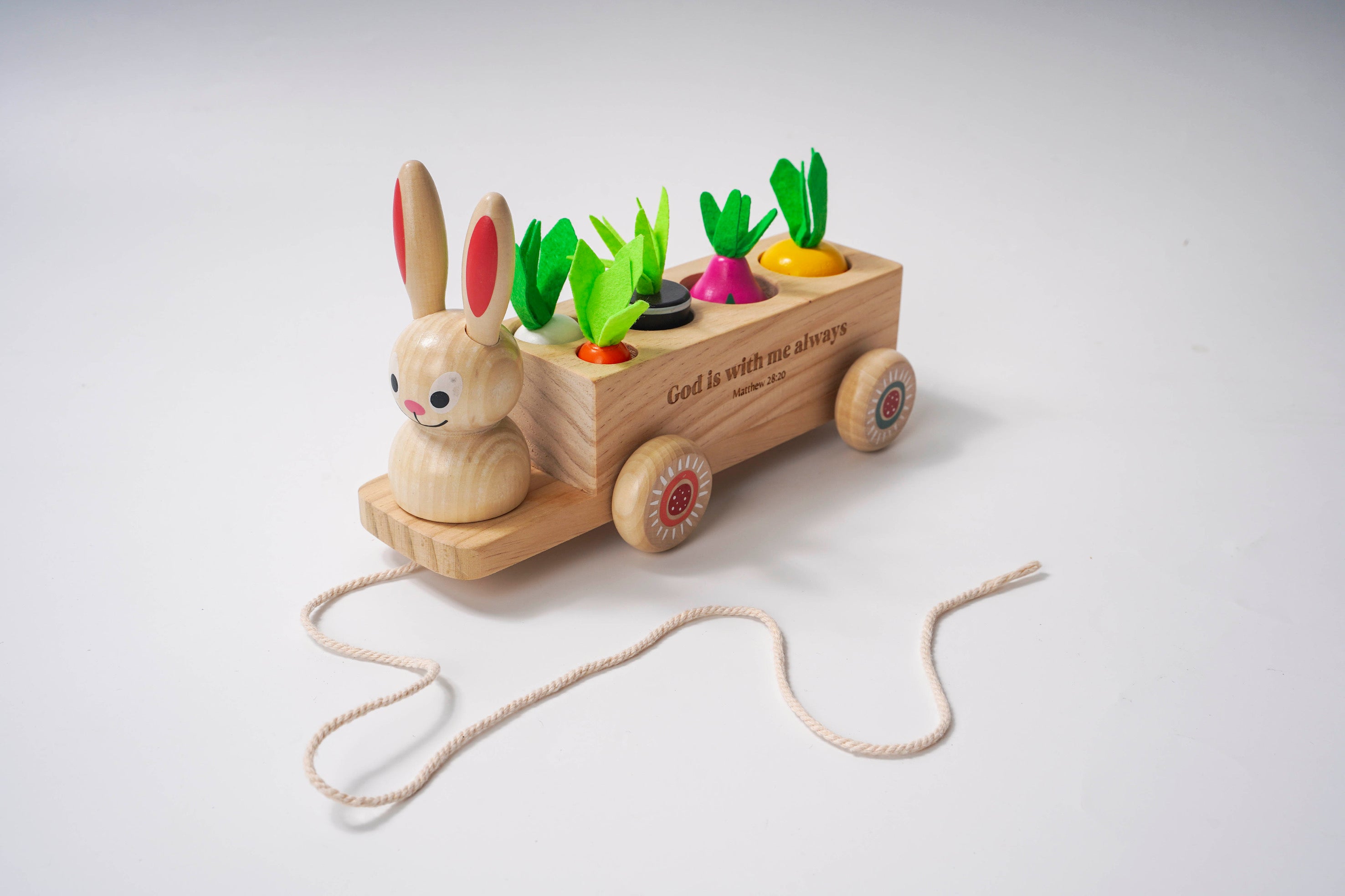 Wooden toy with a rabbit and a cart carrying colorful vegetables on a light gray background