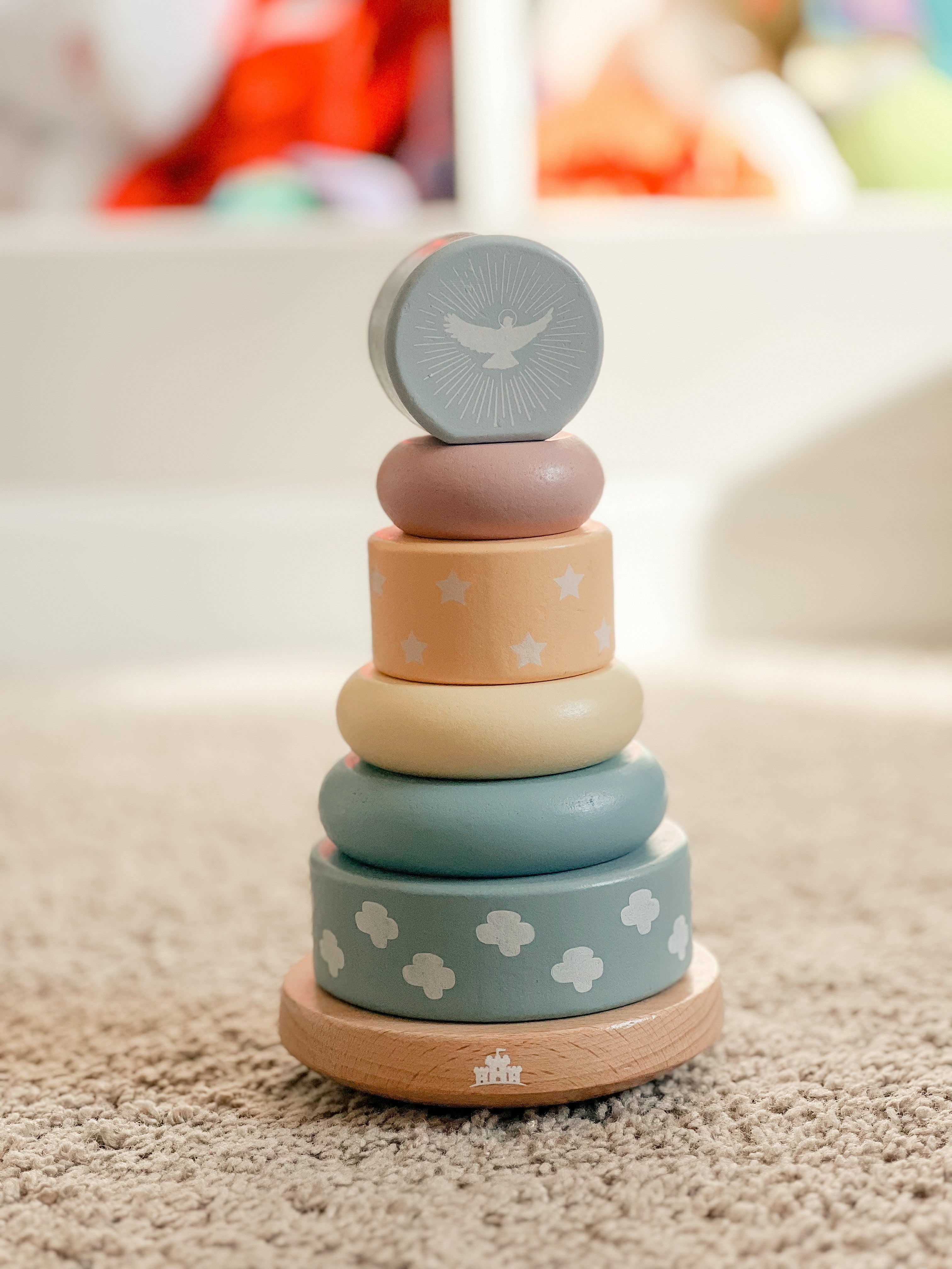Stack of colorful wooden rings with a bird design on a neutral background