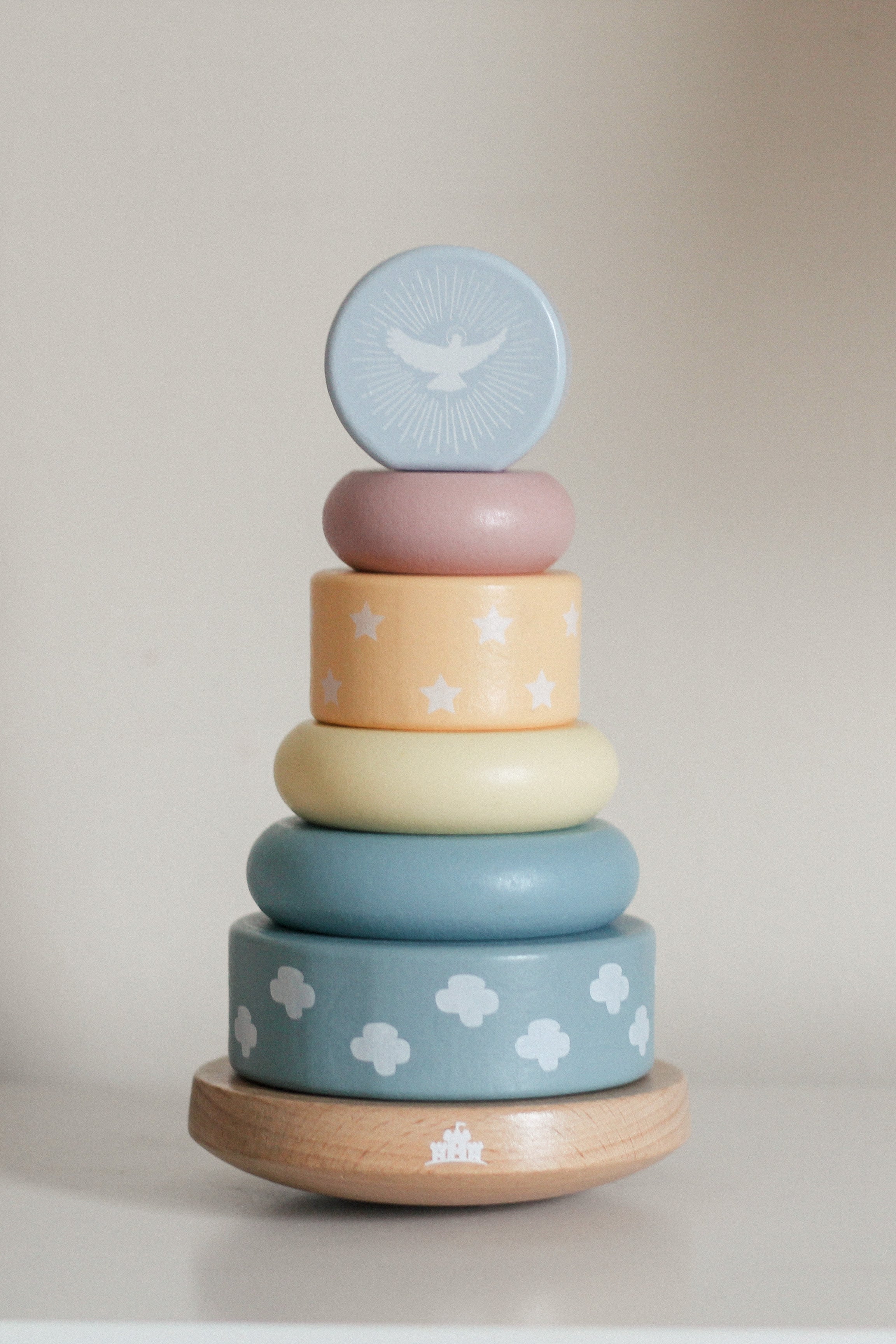 Stack of colorful wooden rings with cloud patterns on a neutral background