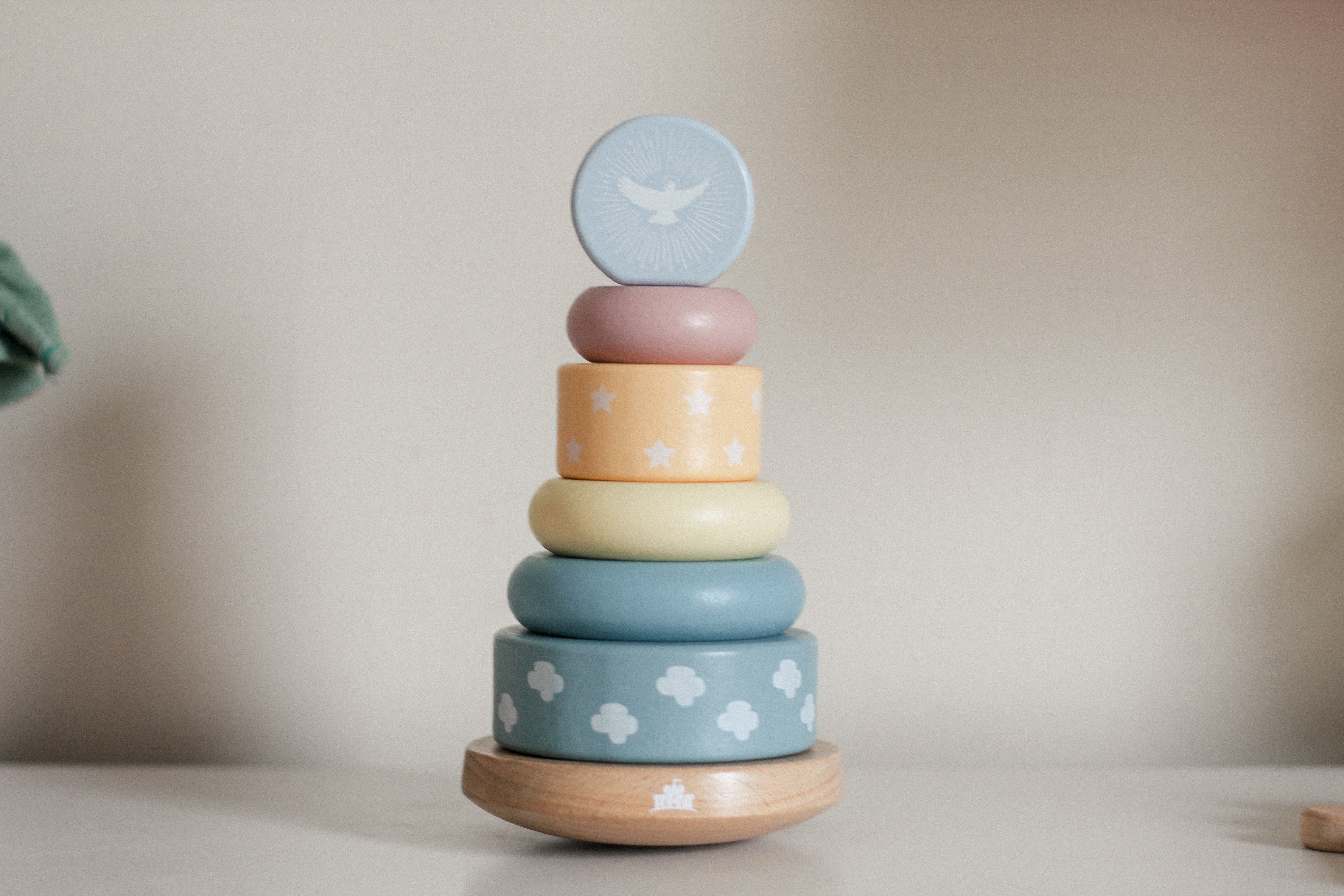 Stack of pastel-colored wooden rings with bird designs on a neutral background