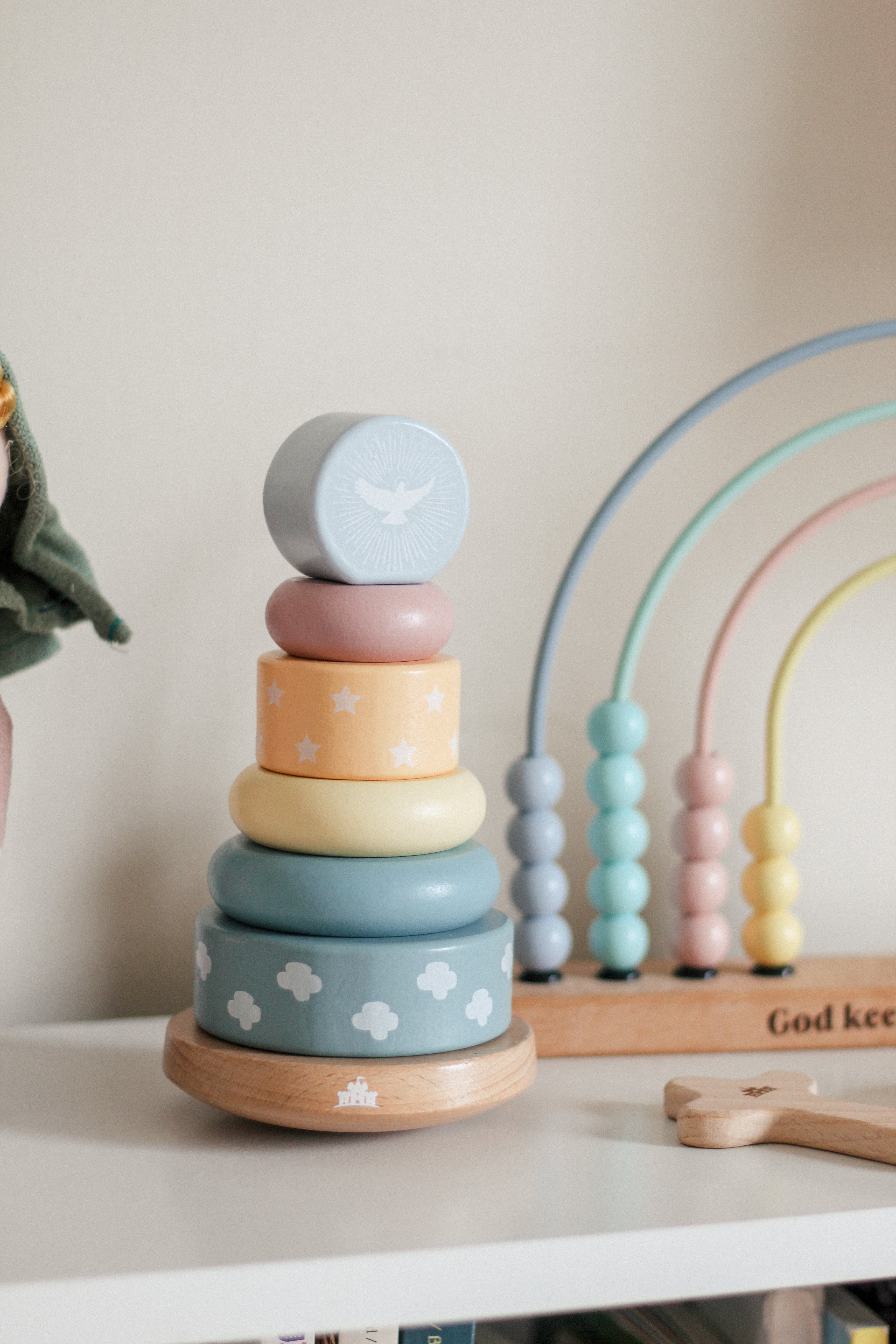 Stack of colorful wooden rings with a rainbow toy in the background