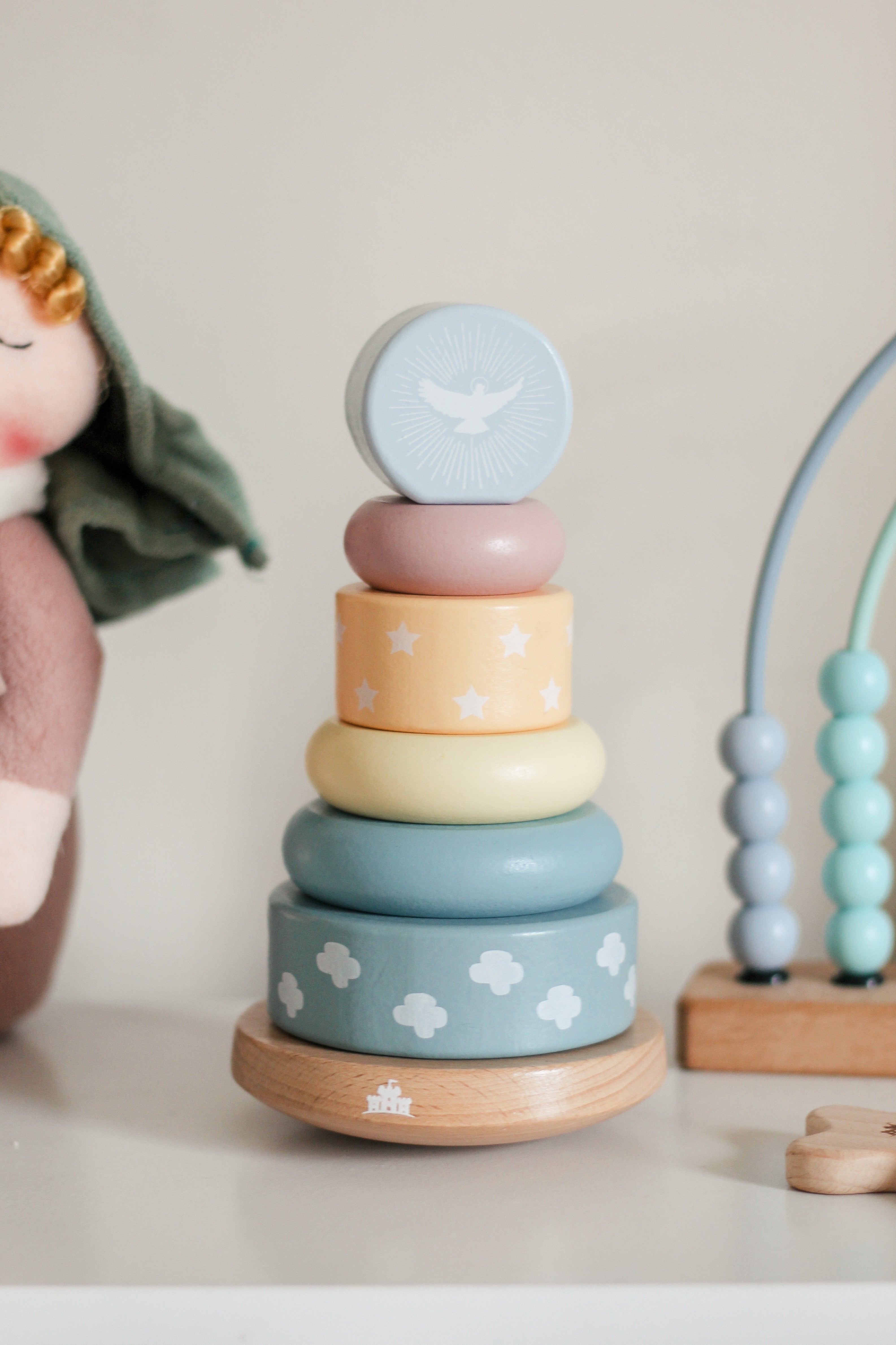Stack of colorful wooden rings with cloud pattern on a neutral background