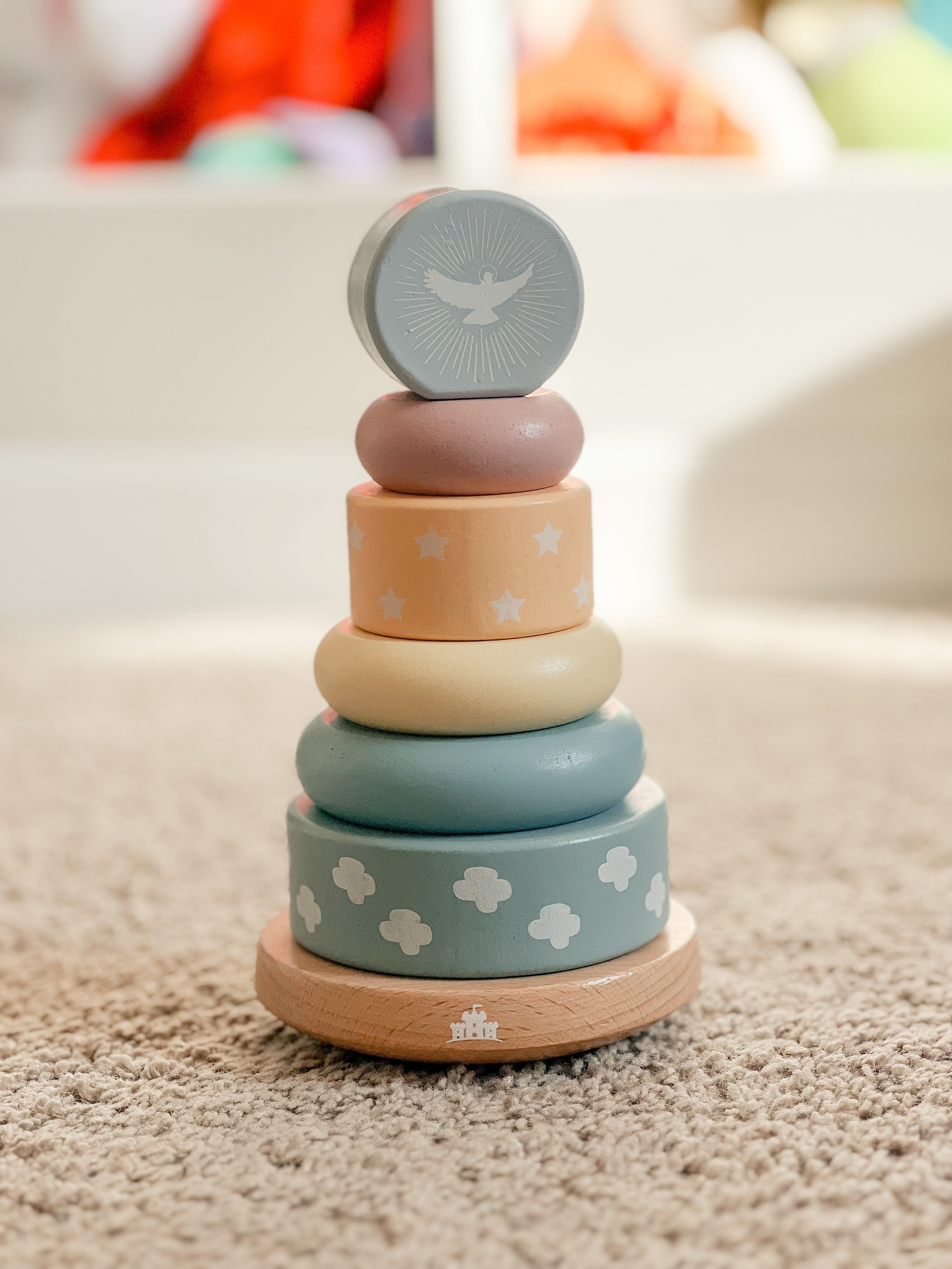 Stack of colorful wooden rings with a bird design on a neutral background