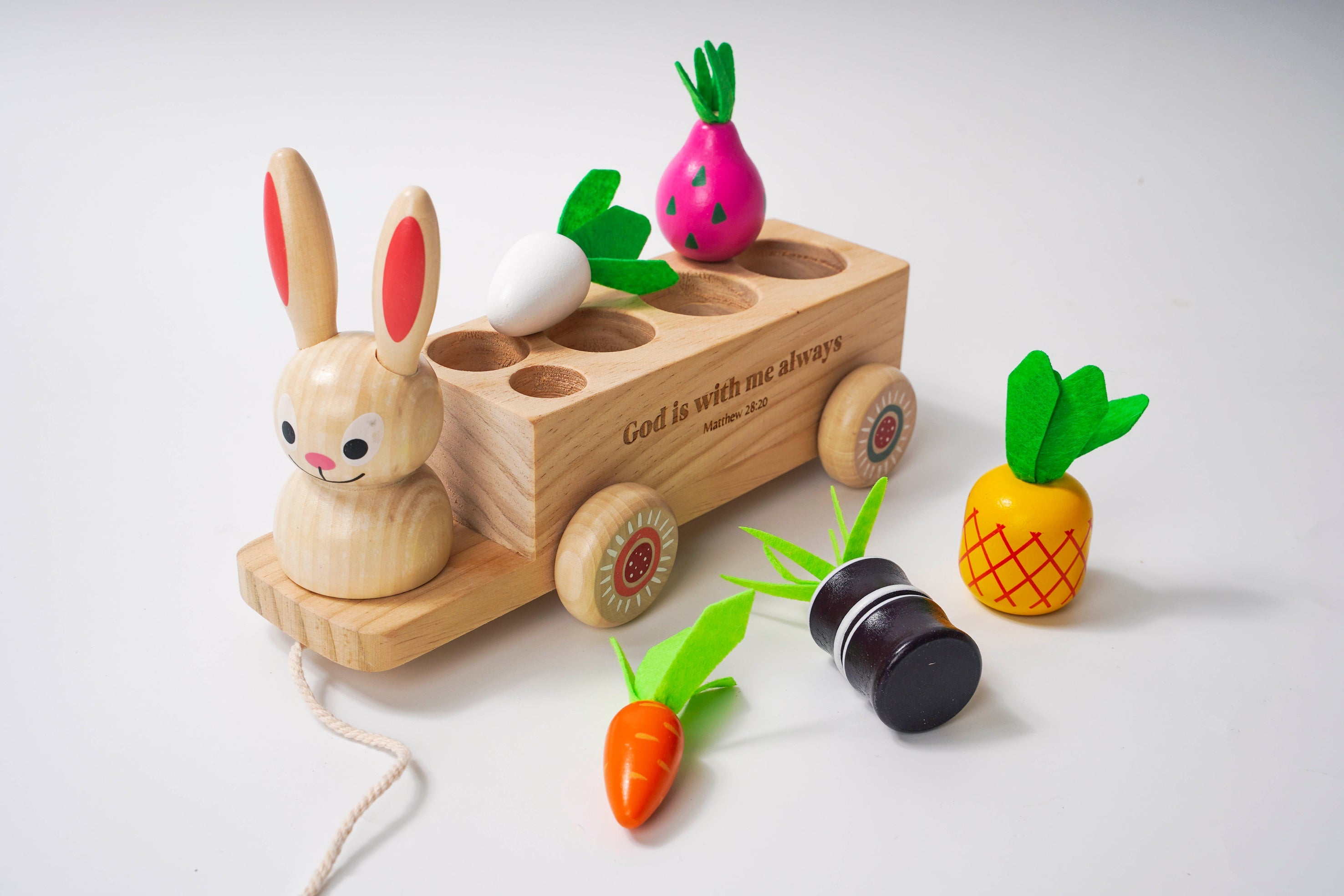 Wooden toy with rabbit figure, carrot, radish, and pineapple on a white background