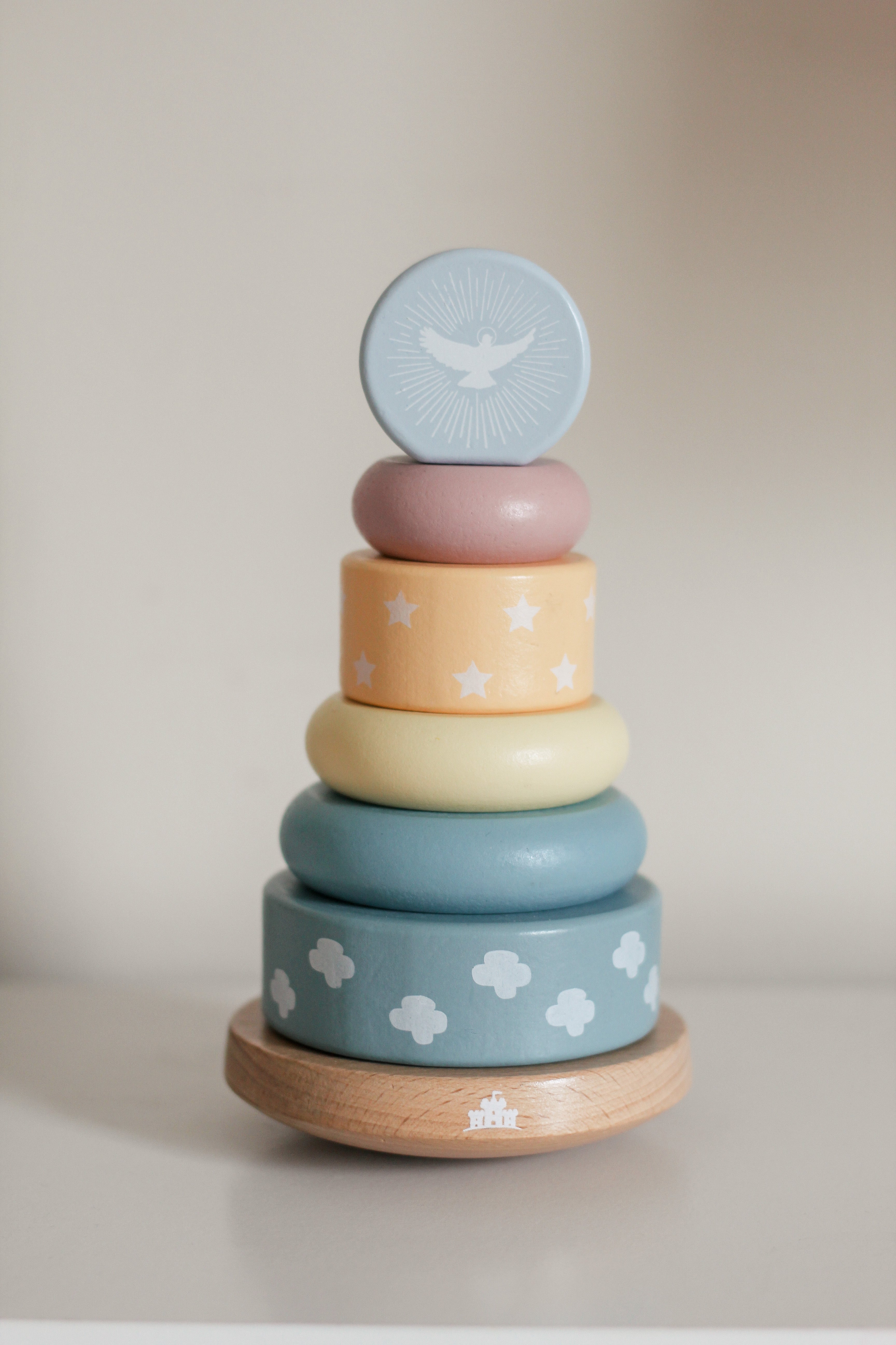 Stack of colorful wooden rings with star and cloud patterns on a beige background