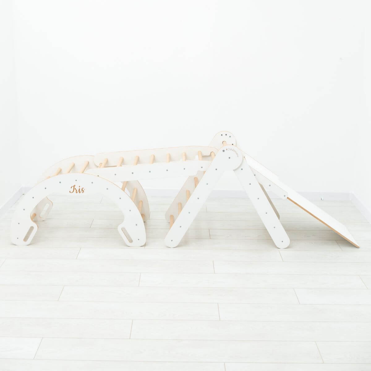 White baby crib with wooden frame on a light wooden floor