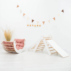 Children's play area with a pink chair and wooden slide on a white floor.