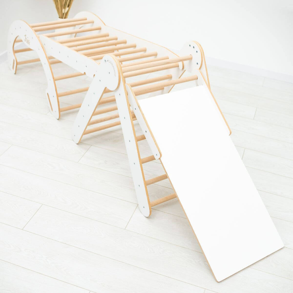 Children's wooden climbing toy with slide on a white floor