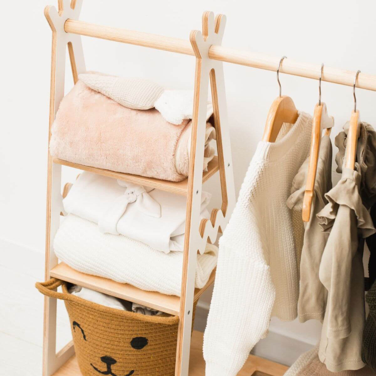 Wooden clothing rack with folded clothes and hanging garments in a room setting.