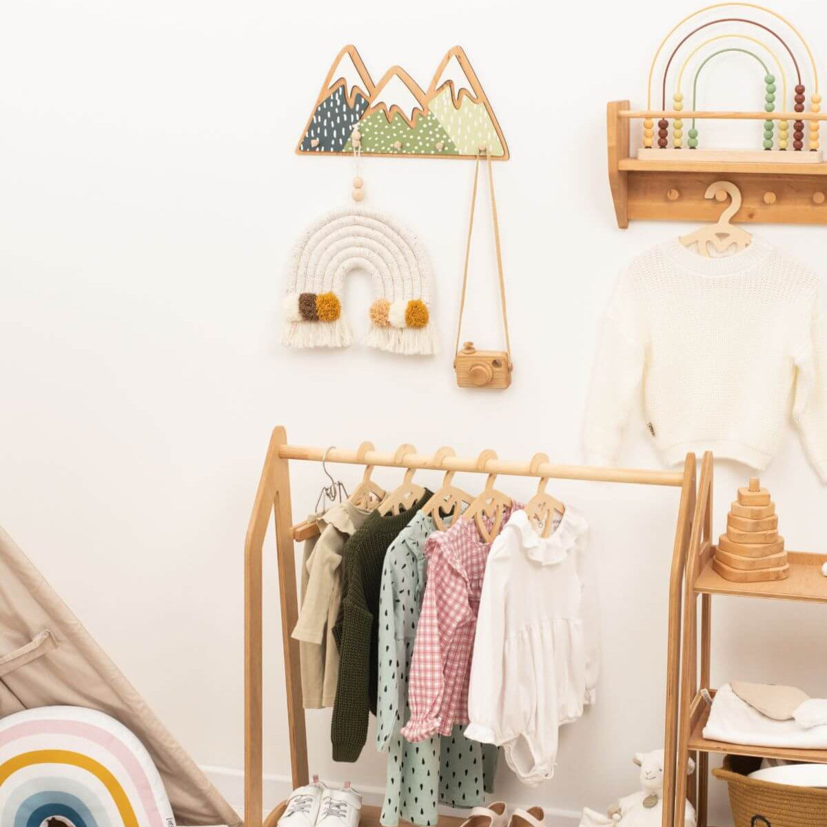 Children's room with wooden rack displaying clothes, wall decorations, and shelves.