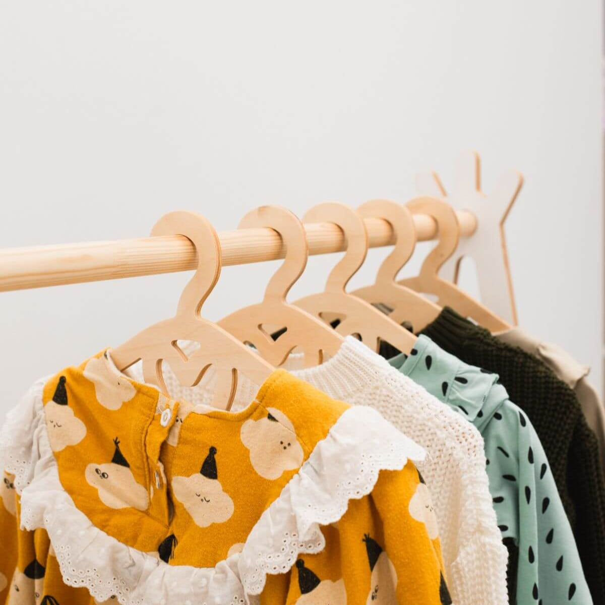 Children's clothing on wooden hangers against a white background