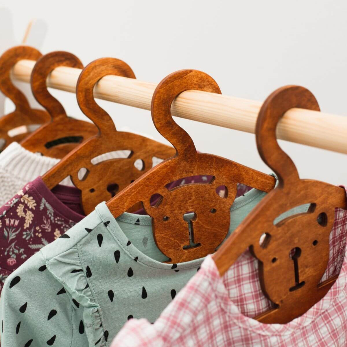 Wooden hangers shaped like bears with children's clothing on a white background