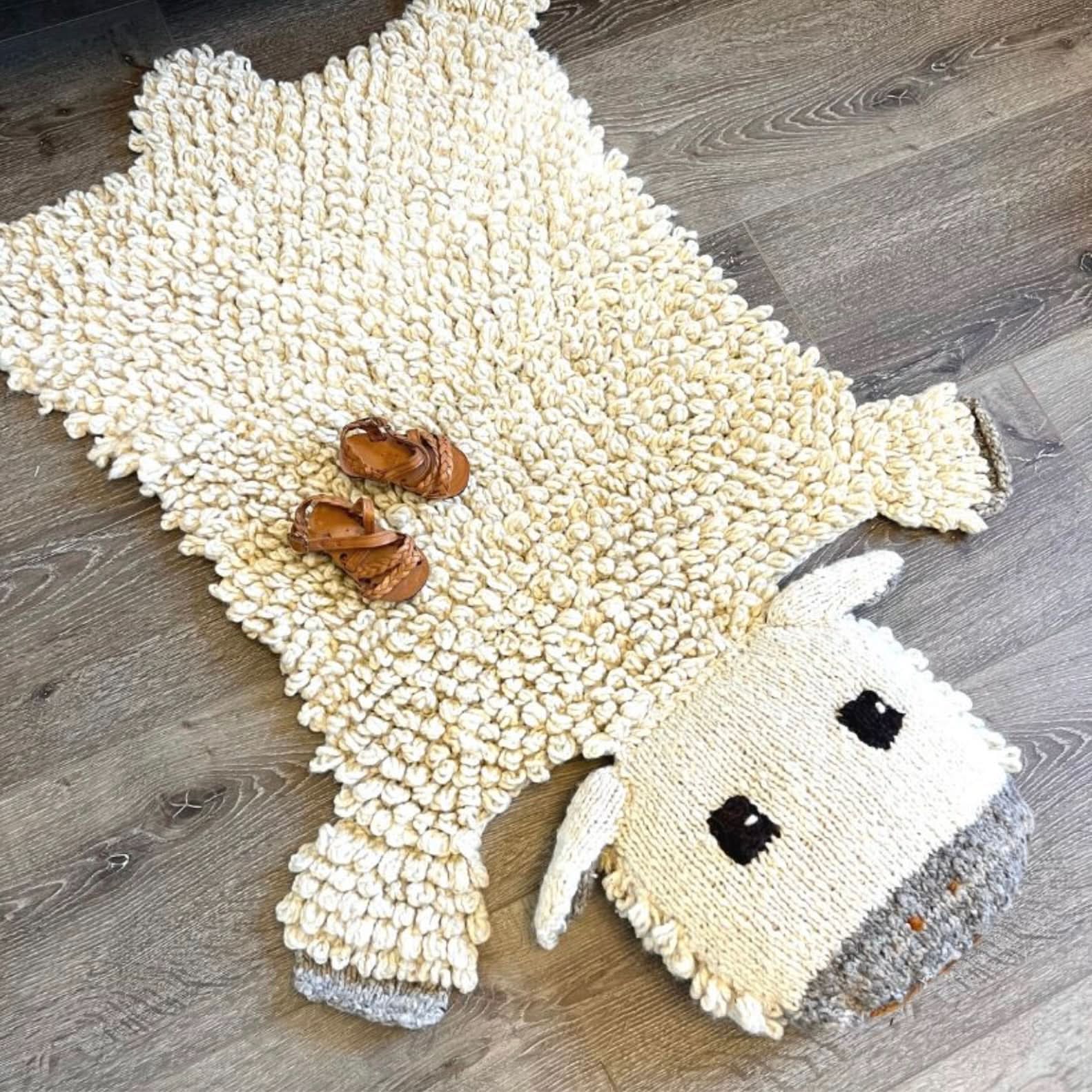 Organic wool sheep nursery rug on white background showing hand-knit texture and design