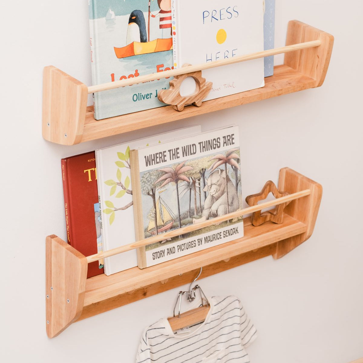 Wooden wall shelf with children's books and a small bag on a white wall