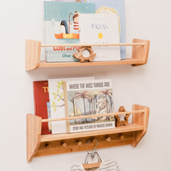 Wooden wall shelf with children's books and a toy on a white wall