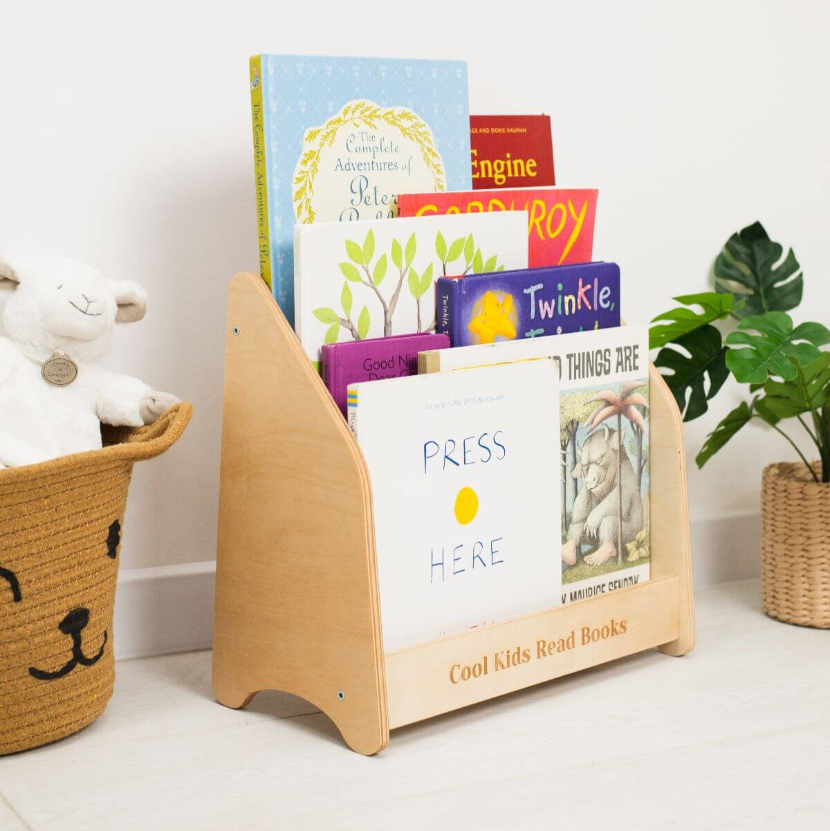 Wooden bookshelf with children's books and a toy on a white surface.