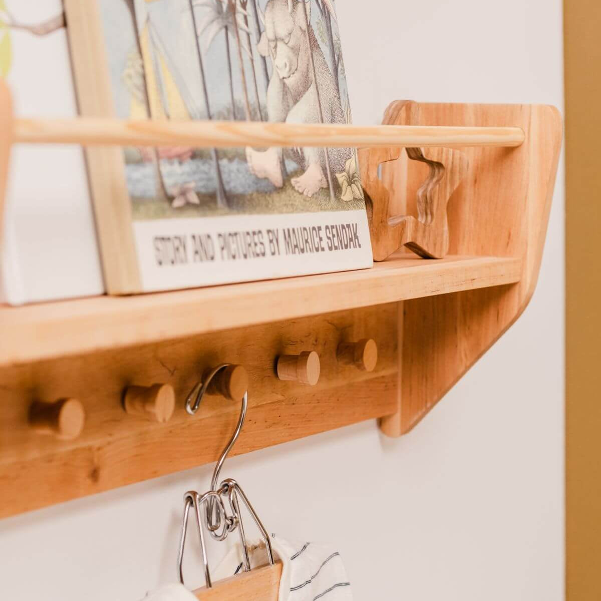 Wooden shelf with hooks and a book titled 'The Tale of Peter Rabbit' by Maurice Sendak.