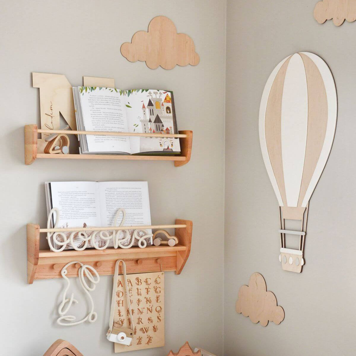 Wooden wall shelves with decorative items against a light gray wall with cloud and hot air balloon decorations.