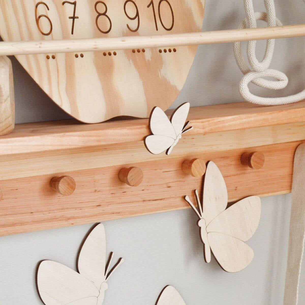 Wooden butterfly decorations on a pegboard against a light gray wall.